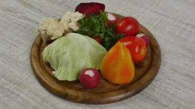 Yuvarlak kahverengi ahşap bir tahta üzerinde güzel istiflenmiş taze salata sebzeleri. Vejetaryenlik, vejetaryenlik, çiğ yiyecekler sağlıklı yaşam tarzı. Sağlıklı beslenme ve uzun yaşam.