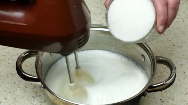 料理人は 生卵の白を鉄鍋に電動ミキサーでホイップします 女性の手のクローズアップは 電動ミキサーで砂糖を加えて卵白からメレンゲを作る 自家製の甘いデザート — ストック動画