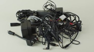 Eski kablo yığını, bağlantılar ve şarj cihazları, arka planda izole edilmiş. Modern cihazlar için eski kablolar, bağlantılar ve şarj cihazları ışık arka planına yakın çekim. Geri dönüşüm sorunu kavramı.