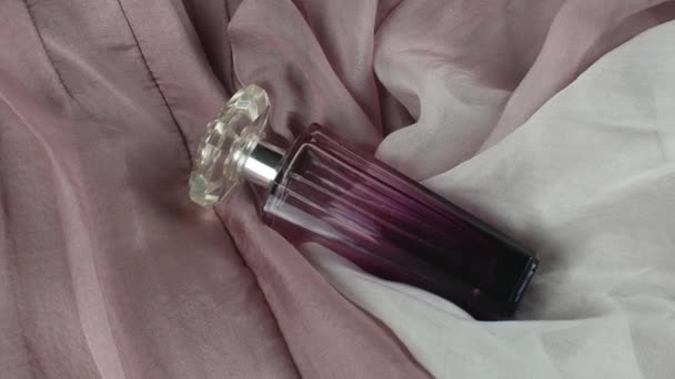 原装透明玻璃瓶中的一种女性香水 在不同色调的粉红色丝质折叠式面料背景上 平躺在床上从上面看 — 图库视频影像