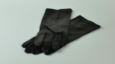 Hafif arka planda zarif kadınların deri eldivenleri. Açık arkaplanda izole edilmiş bir çift yeni siyah deri eldiven. Soğuk mevsim için kıyafet konsepti.