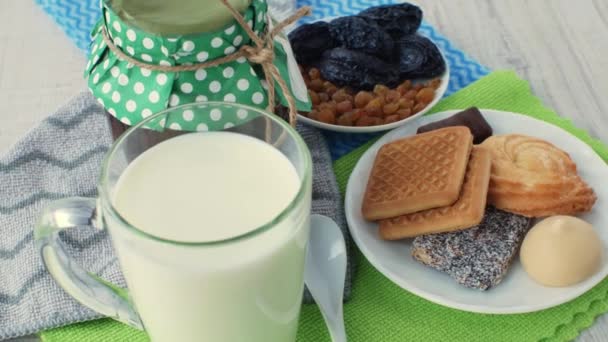 一杯新鲜的天然牛奶 一罐果酱 一茶匙白茶 一碟干果 一碟饼干和甜食在多色餐巾纸上 奶类食品概念 — 图库视频影像