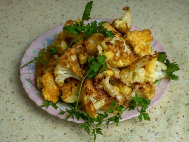 Kızarmış gevrek karnabahar parçaları taze yeşil maydanoz serpiştirilmiş beyaz bir tabağa serpilmişti. Dairesel paranoyak. Doğal sebze diyeti kavramı.