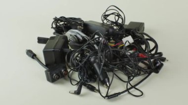 Modern cihazlar için eski kablolar, bağlantılar ve şarj cihazları hafif arka planda yakın plan. Eski kablo yığını, bağlantılar ve şarj cihazları, arka planda izole edilmiş. Aygıt eskitme kavramı.