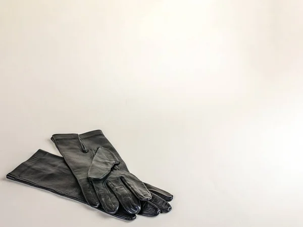 A pair of new black leather gloves isolated on a light background. Graceful female black leather gloves on a light background. The concept of modern fashion clothes.