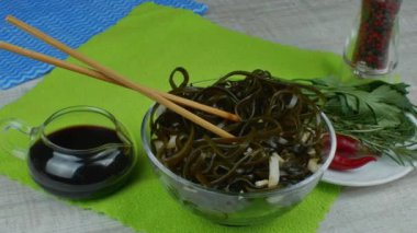 Bir kasede taze yosun uyandı. Cam bir kasede sırılsıklam yeşil bir yosun. Japon yemeği. Çubukla yosun ye. Geleneksel Japon deniz ürünleri.