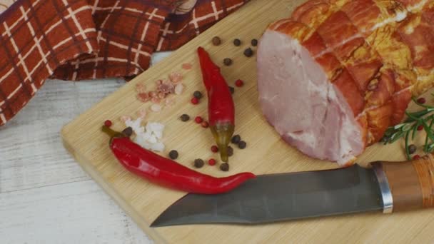 伝統的なハムは 彫刻ナイフ カラフルなオールスパイス 赤唐辛子 パセリ ディル バジルで木製のまな板に 豚肉の旨みがギュッと詰まったお肉スナックのコンセプト — ストック動画