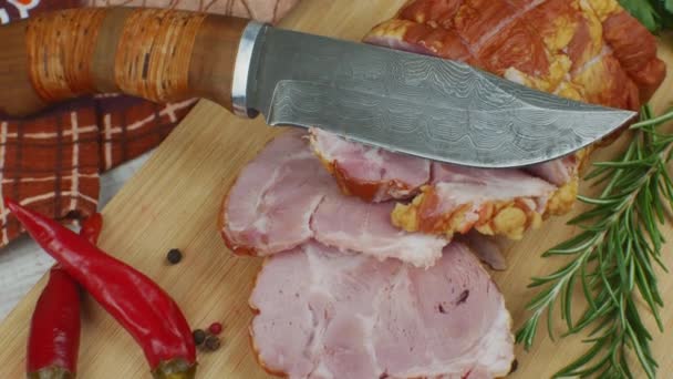 在木制切菜板上切成片的多汁猪肉火腿 旁边是一把雕刻刀 多色多香豆 红辣椒 茴香和罗勒 美味肉制品的概念 — 图库视频影像