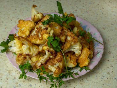 Kızarmış karnabahar iştah açıcı beyaz bir tabakta çırpılmış yumurtaların içinde taze maydanozla serpilmiş. Yakın çekim görüntüsü. Ekolojik sebzelerden lezzetli ve sağlıklı yiyecek kavramı..