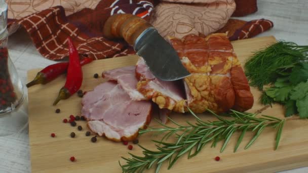 一片多汁和美味的培根切碎成片 放在木制的切菜板上 上面有一把雕刻刀 多种颜色的多香豌豆 红辣椒 茴香和罗勒 烹调肉类的概念 — 图库视频影像