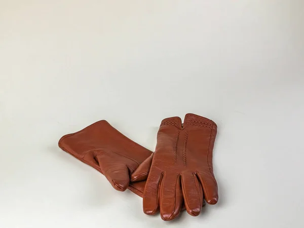 A pair of new brown leather gloves isolated on a white background. Graceful womens brown leather gloves on a white background. The concept of modern fashion clothes.