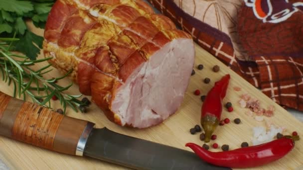 木制切菜板上有一块多汁的猪肉火腿 旁边是一把雕刻刀 多色多香豆 红辣椒 茴香和罗勒 美味肉制品的概念 — 图库视频影像