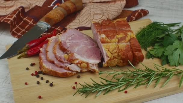 木製のまな板では スライスされたジューシーなポークハム ナイフを彫る 赤唐辛子 多色のオールスパイス パセリ ディル バジル おいしい豚製品のコンセプト — ストック動画
