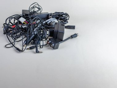 Modern cihazlar için eski kablolar, bağlantılar ve şarj cihazları hafif arka planda yakın plan. Eski kablo yığını, bağlantılar ve şarj cihazları, arka planda izole edilmiş. Aygıt eskitme kavramı.