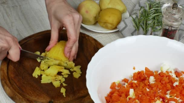 一位家庭主妇在木制切菜板上用菜刀切煮土豆 并把切好的土豆放在一个碗里准备蔬菜沙拉 女性的手紧握着 素食主义的概念 — 图库视频影像