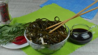 Bir kasede taze yosun uyandı. Cam bir kasede sırılsıklam yeşil bir yosun. Japon yemeği. Çubukla yosun ye. Geleneksel Japon deniz ürünleri.