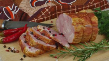 Slices of juicy and delicious pork bacon on a wooden cutting board with a carving knife, multi-colored allspice peas, red hot peppers, parsley, dill and basil. The concept of meat products.