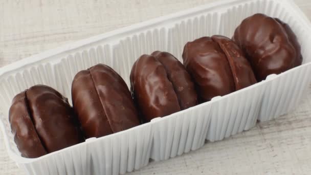 棉花糖在一个白色塑料包装的巧克力釉中 一个巧克力棉花糖包裹的特写镜头躺在一张轻薄的桌子上 糖果糖的概念 — 图库视频影像