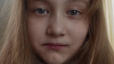 Sarışın, uzun saçlı neşeli bir kız çikolatalı marşmelov yiyor. Mutlu ve memnun bir kızın yüzü çikolata kaplı şekerlemelerle kaplıdır. Mutlu çocukluk kavramı.