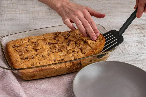 Bir kaseden kesilmiş elmalı turta parçaları bir tabağa konur. Bir kadının eli spatulayla yakın plan çekilirken kesilmiş meyveli turtayı bir tabağa koyar. Tatlı bir tatlı için ev yapımı hamur işleri..