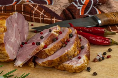 Lezzetli ve lezzetli pastırma dilimleri ahşap bir kesim tahtasıyla dilimlenmiş, çok renkli bezelye, kırmızı acı biber, maydanoz, dereotu ve fesleğen. Et pişirme kavramı.