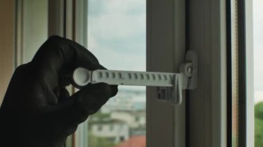 Pencere açma sınırlayıcısını ayarlayan inşaat eldivenli bir adamın yakın çekimi. Plastik bir pencere çerçevesinde pencere durdurma ayarları. Plastik pencerelerin modern aksesuarları. Modern pencere çerçeveleri.