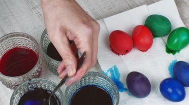 Dişi, renkli tavuk yumurtalarını beyaz kağıt peçeteye bırakır, yumurtaları bardaklardan besin boyasıyla çıkarır. Paskalya yumurtası pişirip boyamak. Mutlu Paskalyalar.