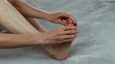 Kadın ayak parmaklarına nemlendirici kullanarak masaj yapıyor. Ayak masajını canlandırıyorum. Ayak refleksolojisi yapan kadın ellerinin yakın çekimi. Evde spa tedavisi. Cilt kremi kullanan kadın vücudu kavramı.