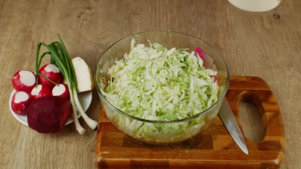 家庭主妇用盐和她的手把切碎的卷心菜放在玻璃碗里 用卷心菜 红萝卜 红甜菜 芹菜根等调味蔬菜沙拉 素食和生食 — 图库视频影像