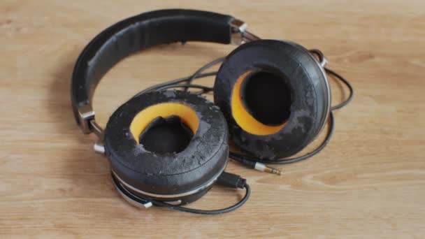旧的破碎的耳机在一个轻型木制桌子上的特写 电气设备和电气设备修理的概念 用于高质量听音乐的耳机 — 图库视频影像