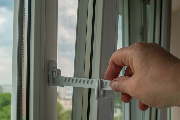 Pencere açma sınırlayıcısını ayarlayan bir adamın yakın çekimi. Plastik bir pencere çerçevesinde pencere durdurma ayarları. Plastik pencerelerin modern aksesuarları. Modern pencere çerçeveleri.