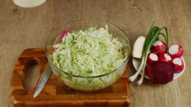 Bir kadının el tuzlama ve salata kasesinde doğranmış beyaz lahana karıştırma yakın çekimi. Taze sebze salatası hazırlıyorum. Vejetaryenlik ve çiğ gıda kavramı sağlık için iyidir..