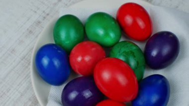 Farklı renklerde boyanmış renkli Paskalya tavuğu yumurtaları mutfak masasındaki beyaz bir tabakta yatıyor. Paskalya bayramı ve boyalı Paskalya yumurtaları kavramı. Hıristiyan inancıyla Paskalya. 