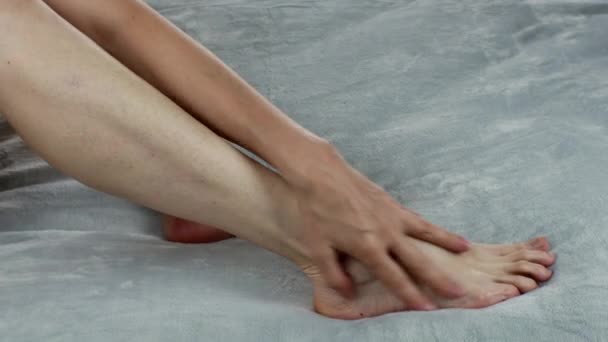 一个女人按摩她的脚 并用奶油润滑她的腿 恢复足底按摩的活力妇女的脚部保健 温泉治疗在家里 女性身体护理的概念 保湿脚霜 — 图库视频影像