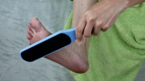 这个女孩用磨刀机擦拭脚后跟的皮肤 脚在家里照顾 切除女性脚后跟上的玉米 在家的教育 腿护肤的概念 — 图库视频影像