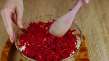 Kadın eli, cam salata kasesinde doğranmış sebzeleri silikon spatulayla karıştırıyor. Taze sebze salatası hazırlıyorum. Sağlıklı beslenme kavramı bir yaşam tarzı olarak.