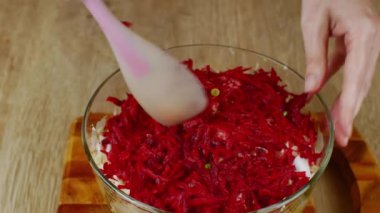 Aşçı cam bir kasede silikon kaşıkla kesilmiş sebzeleri karıştırır. Ev mutfağında taze sebze salatası pişiriyorum. Doğal gıda kavramı sağlık için yararlıdır..