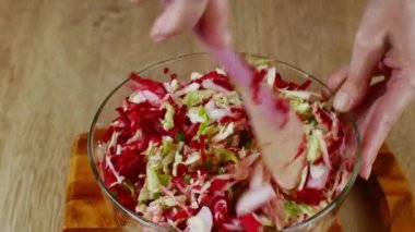 Aşçı cam bir kasede silikon kaşıkla kesilmiş sebzeleri karıştırır. Ev mutfağında taze sebze salatası pişiriyorum. Doğal gıda kavramı sağlık için yararlıdır..