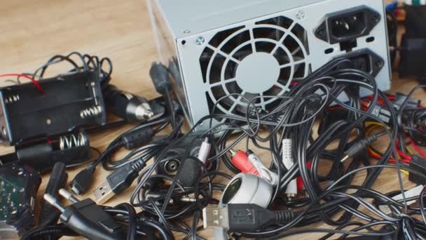 木桌上的一堆堆旧电线 连接线 耳机和充电器 更换电子设备的旧部件和零件 损坏的电子设备及其部件的修理 — 图库视频影像