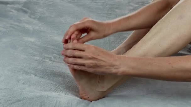 一个女人在按摩她的腿 使用保湿霜治疗皮肤干燥 改善妇女的足部健康 温泉治疗在家里 恢复足底按摩的活力女性身体护理的概念 — 图库视频影像