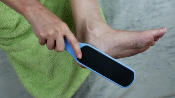 一个女人用双面脚磨擦脚后跟 雌性用磨刀机擦拭脚 清除脚后跟上的老茧 教学工具 脚部护理 妇女健康概念 — 图库视频影像