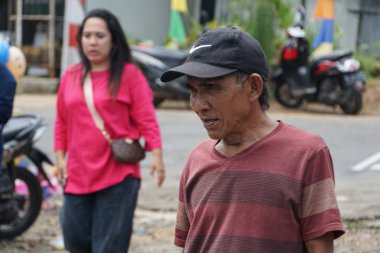 An old man wearing a black hat