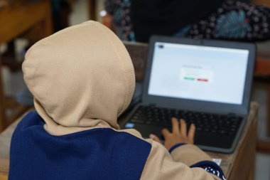 Endonezyalı ilkokul öğrencisi internette bilgisayar kullanarak çalışırken görülmüş.