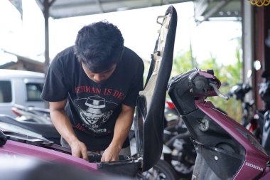 Yazı işleri. Reban, Jawa Tengah, Endonezya - 3 Aralık 2022. Motosiklet tamir eden bir tamirci