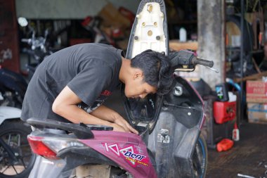 Yazı işleri. Reban, Jawa Tengah, Endonezya - 3 Aralık 2022. Motosiklet tamir eden bir tamirci