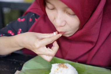 A woman in a hijab is eating crab seafood
