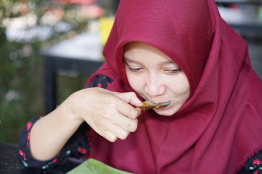 A woman in a hijab is eating crab seafood