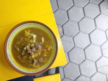 Geleneksel baharatlı keçi körisi, bol soslu ve otlu bir tabakta servis edilir. Otantik Hint mutfağı konsepti