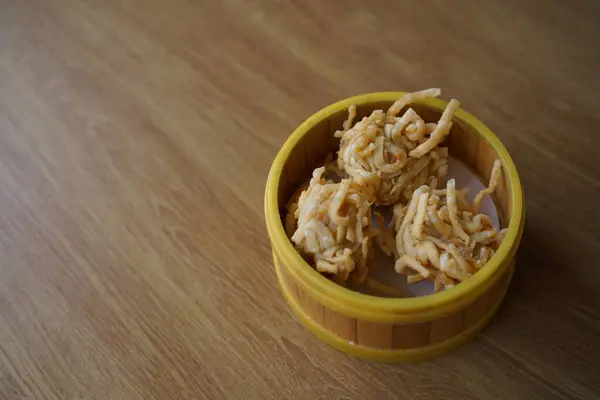 Tahta bir masada, bambu buharlı sepetin içinde üç altın sarısı kızarmış hamur köftesi. Dim Sum kavramı.