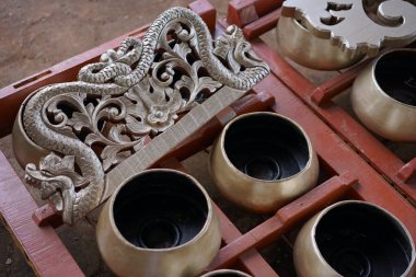 A detailed close-up of a traditional Javanese Kendang drum, featuring an ornate reddish-brown wooden body with gold carvings, used to lead the rhythm in Gamelan music. Indonesian cultural heritage con